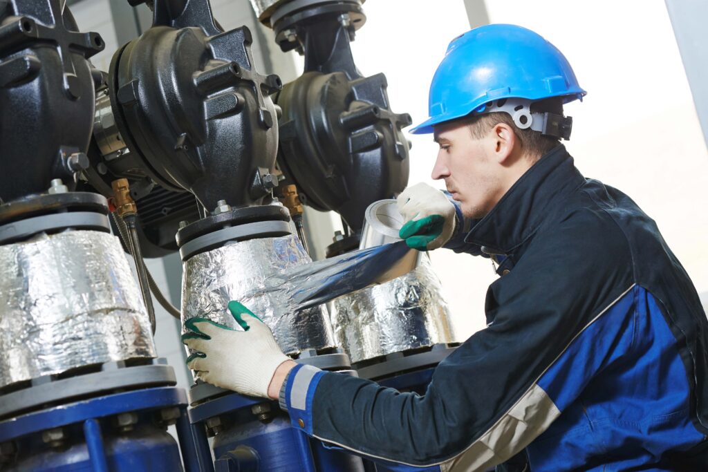 Industrie Isolierer bei der Arbeit. Er isoliert eine Maschine, damit diese Energieeffizienter arbeitet.